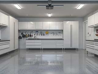 Spacious garage featuring gleaming cabinetry, tool organization, and a smart garage door opener, illustrating advanced custom garage solutions.