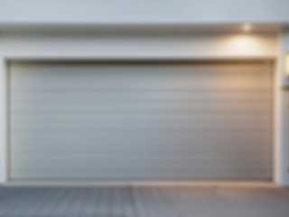 Blurred close-up of a contemporary garage door on a white home with evening lighting, ideal for showcasing modern garage door company services in Altadena.