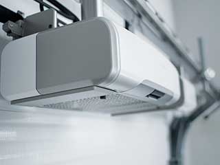 Close-up image of a contemporary garage door opener unit installed on a ceiling, illustrating professional opener installation and repair services.