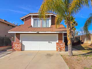 Two-story home featuring a sleek white double garage door, palm trees, and modern exterior details that showcase fashionable garage door trends.