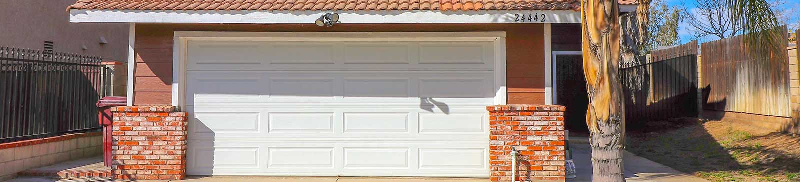 Two-story home featuring a sleek white double garage door, palm trees, and modern exterior details that showcase fashionable garage door trends.