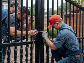 Technicians Providing Professional Gate Repair and Installation Team of skilled technicians performing repair on a black metal security gate at a residential property, exemplifying expert gate service and craftsmanship.