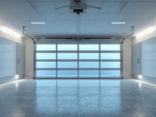 Bright, modern garage with a smart glass-panel garage door, ceiling-mounted Wi-Fi opener, and integrated control panels, illustrating the latest in garage door technology.